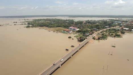 drone-:-flying-back-over-a-concrete-bridge-running-across-the-flooded-river-in-rural-area