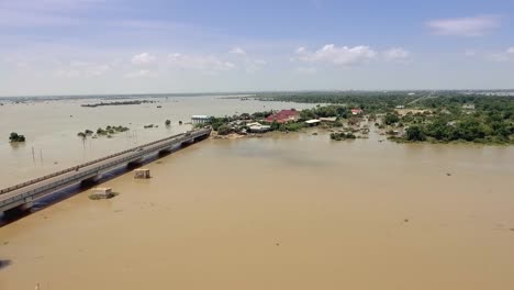 drone-:-flying-over-a-concrete-bridge-running-across-the-flooded-river-in-rural-area