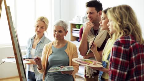 group-of-artists-discussing-painting-at-art-school