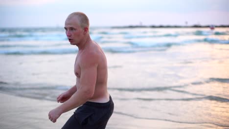 Muskulöse-junge-Mann-üben-Boxen-Übungen-am-Meeresstrand.-Männliche-Sportler-ist-praktizierte-Selbstverteidigung-allein-in-der-Nähe-Meer-Küste.-Training-der-Kampfkünste-im-Freien-bei-Sonnenuntergang.-Slow-Motion-hautnah