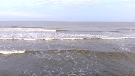 onda-de-las-ondas-llegan-a-la-orilla-lenta.-La-gaviota-vuela-sobre-las-olas