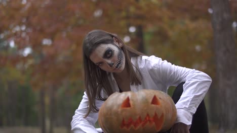 Halloween.-Eine-Mädchen-mit-einem-scary-Halloween-Make-up-sitzt-in-der-Nähe-der-Kürbis