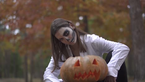 Halloween.-A-girl-with-a-scary-Halloween-makeup-is-sitting-near-the-pumpkin