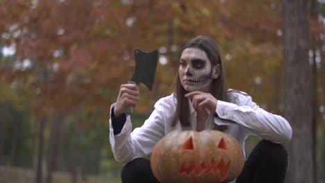 Víspera-de-Todos-los-Santos.-Chica-con-un-maquillaje-de-Halloween-de-miedo-está-sentado-con-el-cuchillo-de-un-carnicero