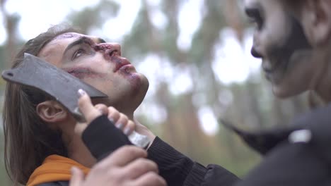 Halloween.-Eine-Mädchen-mit-einem-schrecklichen-Make-up-droht-den-Mann-mit-einem-Messer