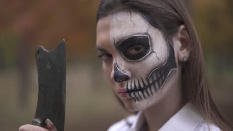 Halloween.-Girl-with-Halloween-make-up-runs-her-finger-along-the-blade-of-knife