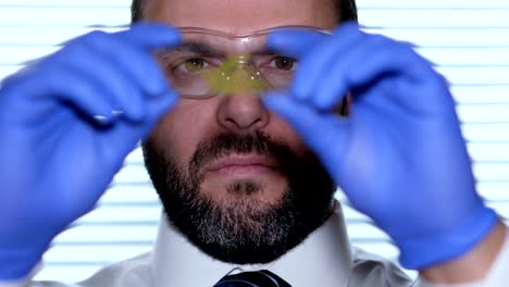 Biologist-examines-sample.-Science,-biology,-ecology.-Professional-scientist-wearing-protective-mask-working-with-herb-samples-in-his-laboratory.-Male-scientist-looking-at-plant-leaf-in-glass-slide.