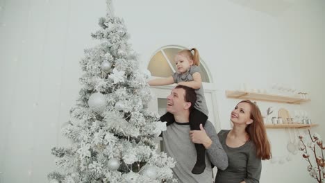 The-family-is-standing-near-the-Christmas-tree,-laughing-talking-and-touching-toys-while-waiting-for-Christmas