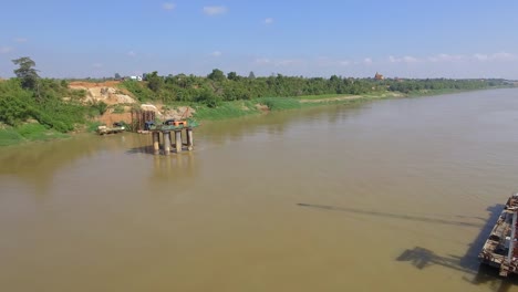 aerial-slider-shot-of-the-bridge-foundation-and-a-barge-mounted-crane-in-river