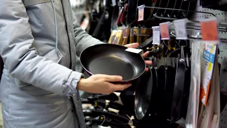 A-young-woman-chooses-a-non-stick-frying-pan-in-the-store.