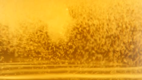 Filling-glass-with-beer-while-bubbles-and-foam-spreading-4K