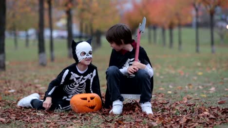 Children-having-fun-with-halloween-carved-pumpkin-in-a-park,-wearing-scary-costumes-and-playing-with-toys