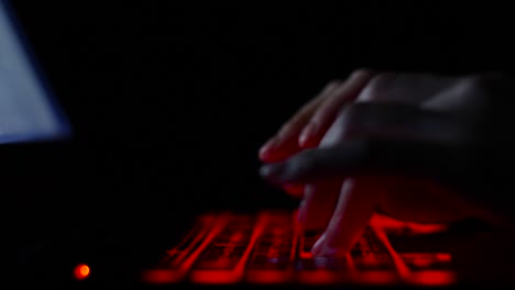 Hacker-Mädchen-Hand-tippen-auf-Tastatur-mit-roter-Hintergrundbeleuchtung