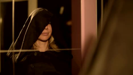 Close-up-of-a-girl-magician-in-front-of-a-mirror-puts-on-the-hood-of-his-suit-time-after-time.-Live-camera.