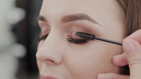 Professional-makeup-artist-woman-paints-eyelashes-to-client-of-beauty-salon