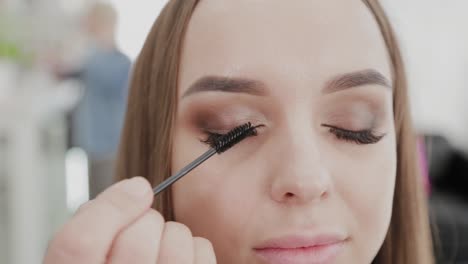 Professionelle-Make-up-Künstler-Frau-malt-Wimpern-an-Kunden-des-Schönheitssalons