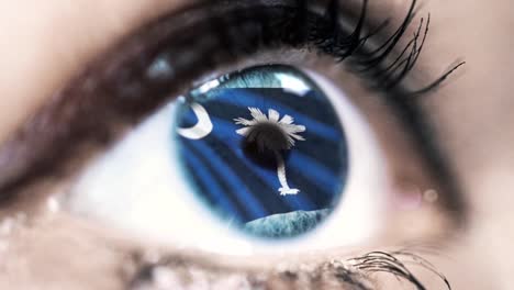 Woman-blue-eye-in-close-up-with-the-flag-of-South-Carolina-state-in-iris,-united-states-of-america-with-wind-motion.-video-concept