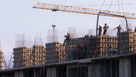 Trabajadores-en-una-obra-de-construcción.-Una-grúa-en-un-sitio-de-construcción-levanta-una-carga