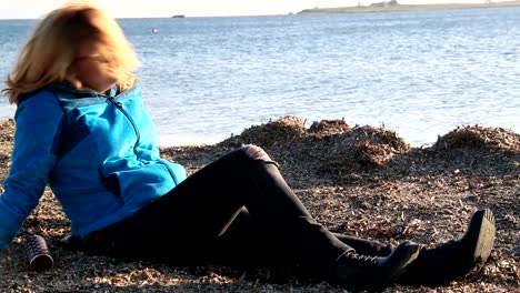 Blonde-sad-woman-sitting-at-the-seaside