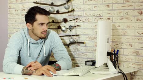 Young-bearded-businessman-in-grey-sweatshirt-working-in-bright-office.