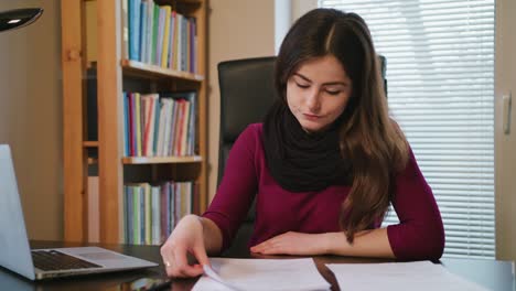 Mujer-abrumada-con-documentos-y-portátil-en-casa