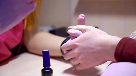 Una-manicurista-profesional-pinta-uñas-al-cliente.-Cubrir-las-uñas-de-gel-con-laca.-FullHD