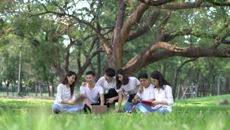 Sechs-Studenten-treffen-Hausaufgaben-zusammen.-Menschen-treffen-im-Park-im-freien-Team.-Mann-und-Frau-mit-Laptop-Computer.-Konzept-der-Bildung,-Teamarbeit,-lernen,-Informationen,-wissen-und-Forschung.