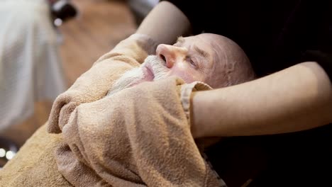 Barber-steam-up-the-face-of-mature-man-with-hot-towel-before-shaving