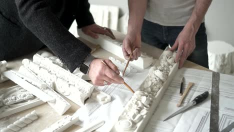 Hands-of-male-sculptor-showing-molding-piece-with-flower-ornament