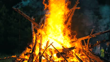 Großes-Lagerfeuer-aus-Zweigen-brennen-in-der-Nacht-im-Wald