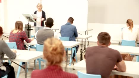 Female-speaker-giving-presentation--in-lecture-hall