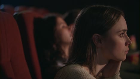 Chica-joven-pensativo-viendo-la-película-en-el-cine.-Rostro-de-mujer-bonita-en-el-cine