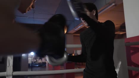 Un-primer-plano-de-un-cuadro-cortado-de-un-entrenador-de-boxeo-es-formación-de-su-alumno.-El-entrenamiento-de-lucha-equipos,-golpes-de-boxeo,-un-propuesto-de-deportes,-boxeo-patas-y-guantes,-preparación-para-la-batalla.-Cámara-lenta