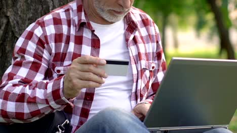 Old-man-paying-for-utilities-with-credit-card,-using-laptop,-money-transaction