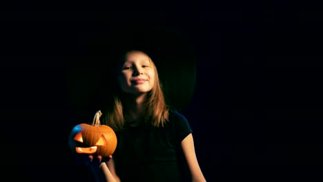 Girl-wearing-black-witch-hat-holding-jack-o'-lanterns