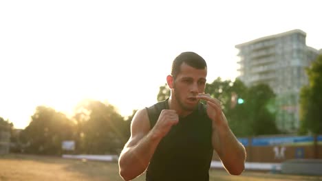 Beschleunigten-Aufnahmen-von-einer-aktiven,-wütend-männlicher-Boxer-während-des-Trainings-Prozess-auf-dem-Natur-Stadion.-Porträt-eines-Mannes-mit-unsichtbaren-Gegner-Boxen,-Stanzen