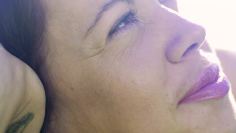 Slow-motion-woman-looks-up-dreaming-siesta,-hand-propping-head-smiling-pleasant