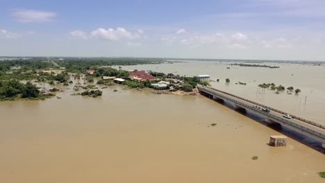 Drone:-volando-sobre-un-puente-de-concreto-que-atraviesa-el-río-inundado-en-zona-rural