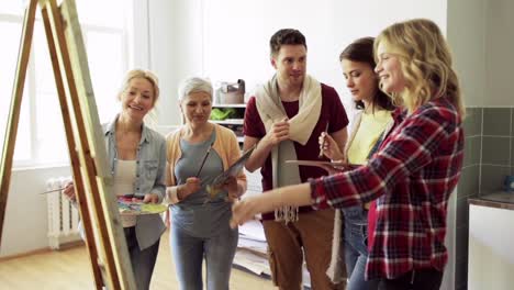 group-of-artists-discussing-painting-at-art-school