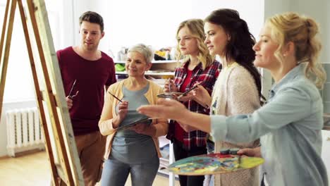 group-of-artists-discussing-painting-at-art-school