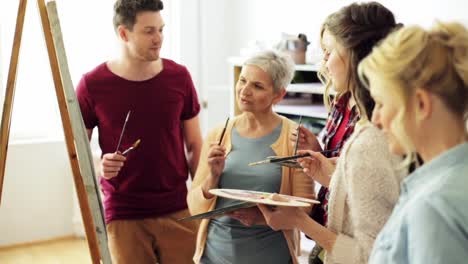 group-of-artists-discussing-painting-at-art-school