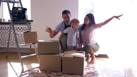 Feliz-familia-con-hijo-pequeño-disfruta-de-nueva-luz-hogar-después-de-las-reparaciones-entre-cajas-de-cartón-con-cosas