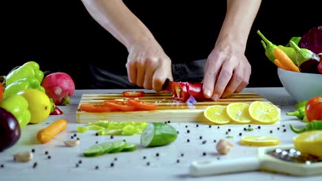 Man-is-cutting-vegetables-in-the-kitchen,-slicing-red-bell-pepper