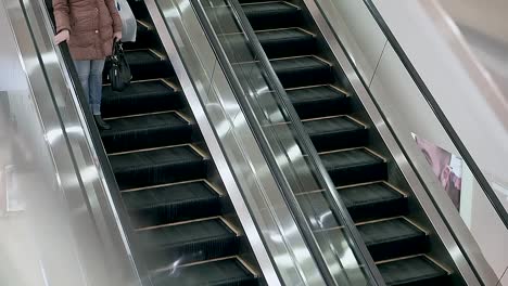 escalera-mecánica-en-el-centro-comercial,-funciona.-Personas-paseo,-mujer-y-su-hijo