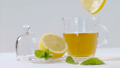 Té-de-hierbas-se-vierte-en-tetera-transparente,-hojas-de-limón-y-menta-alrededor-de-75-fps-lenta