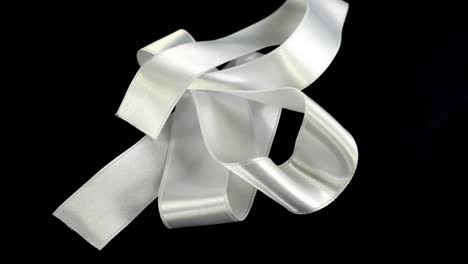 Satin-ribbon-on-a-black-background.-Slow-motion.