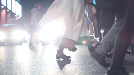 Pedestrians-crossing-street-at-night-at-120fps-slow-motion.-Lens-flares-of-cars-in-the-background-with-crowd-of-people-in-the-foreground.-Couple-with-stroller-crossing-the-street