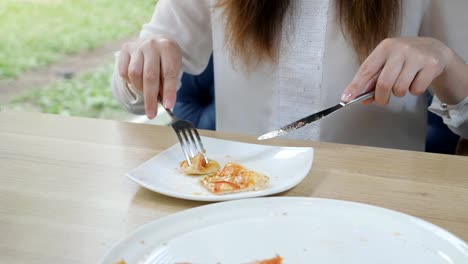 Schneiden-ein-Stück-Pizza-mit-Messer-und-Gabel-auf-einem-weißen-Teller