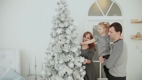 Die-Familie-steht-in-der-Nähe-der-Weihnachtsbaum,-lachen,-reden-und-Spielzeug-zu-berühren,-während-des-Wartens-auf-Weihnachten