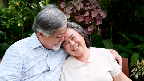 Senior-couple-sitting-and-drinking-red-wine-together-in-home-garden.